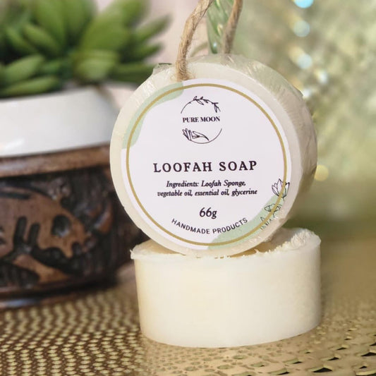 Loofah soap with a label on a woven surface, blurred plant in the background