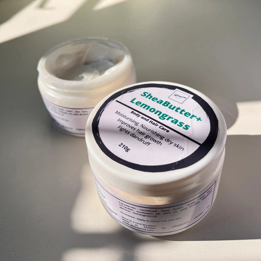 Two containers of shea butter with labels on a light surface.