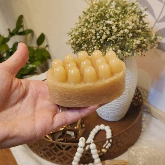 Hand holding a textured soap bar with decorative items in the background