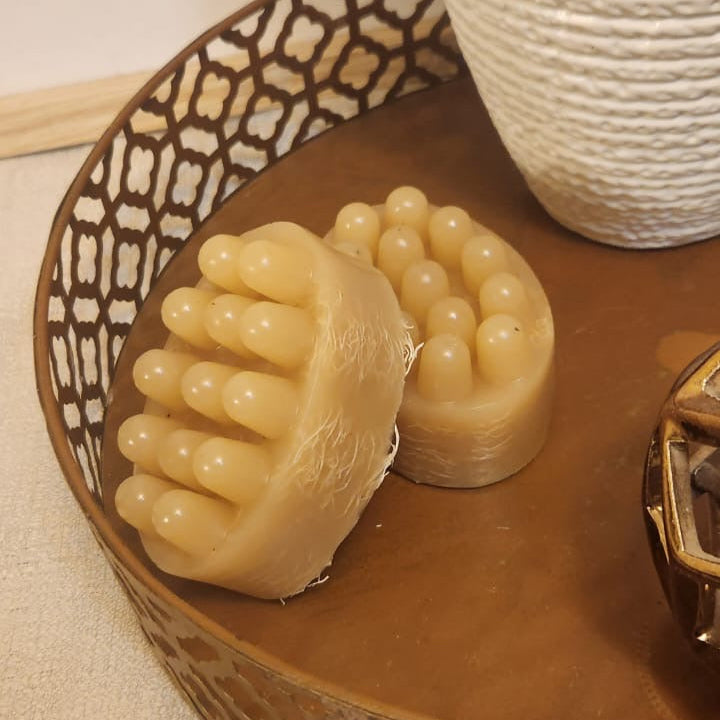 Two beige soap bars with a textured surface on a wooden tray.